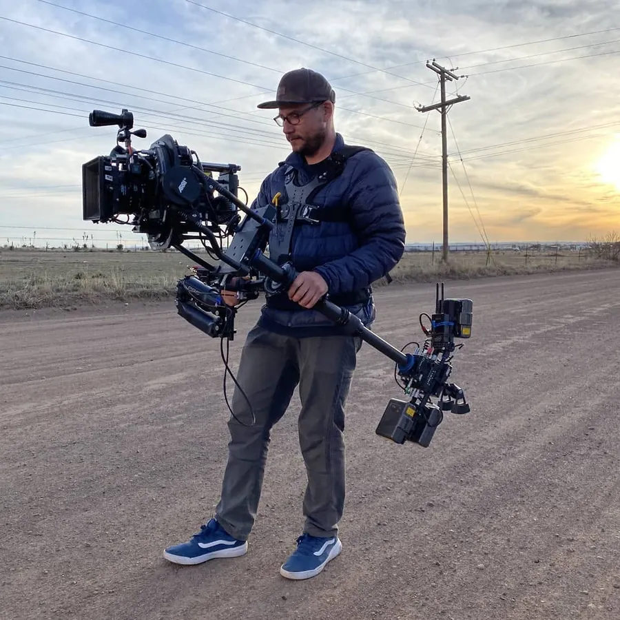 Michael Deitch carrying a Steadicam with an ARRI camera on a dirt road at sunset